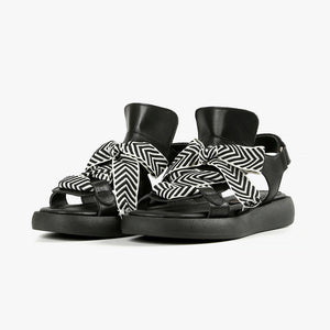 front view of a pair of the all black footwear bowlace sandal