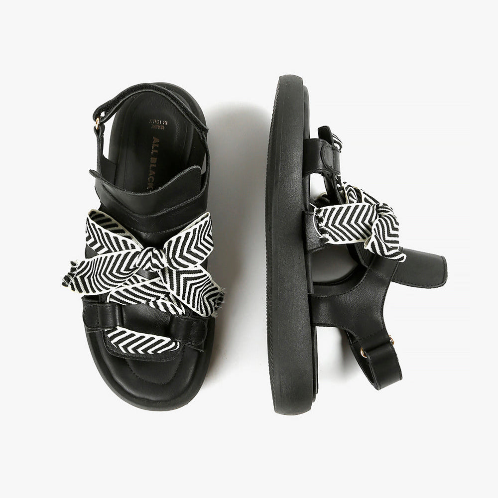 Birdseye view of a pair of the all black footwear bowlace sandal