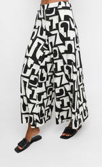 Load image into Gallery viewer, Front bottom half view of a woman wearing the ozai n ku puzzle letterpress palazzo pants
