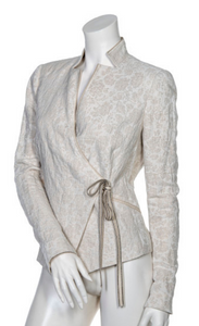 Front view of a mannequin wearing the beate heymann jacquard wrap jacket. This jacket is beige with a floral beige print and a tie on the left front side to close the jacket.