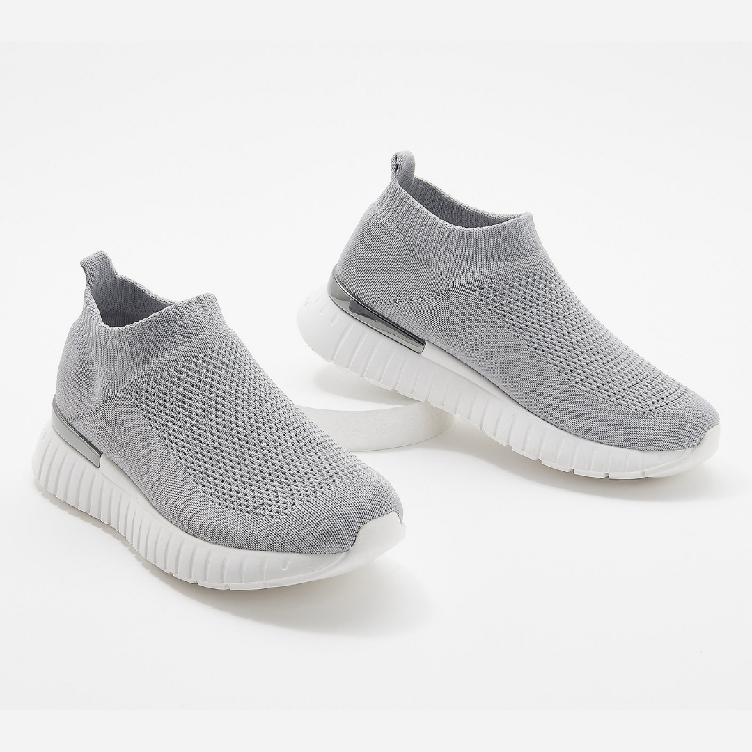 Outer and inner view of the ilse jacobsen tulip mesh slip on sneaker in grey. This sneaker is sock-like with a white sole and a silver embellishment around the heel.