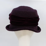 Load image into Gallery viewer, back view of the lillie &amp; cohoe aubergine wool jeanette hat. This hat is wine/purple colored and has a rounded brim and a velvet band that wraps around the crown to make a bow on the side.
