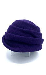 Load image into Gallery viewer, Left side view of the lillie &amp; cohoe boiled wool lexi purple hat. This has a tiered look on the crown and a folded brim that stitches up on the right side
