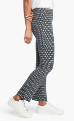 Load image into Gallery viewer, Right side, bottom half view of a woman wearing the Nic + Zoe Ponte Ikat Pant. These pants are indigo with white speckled print. They have a straight leg and sit above the ankles.
