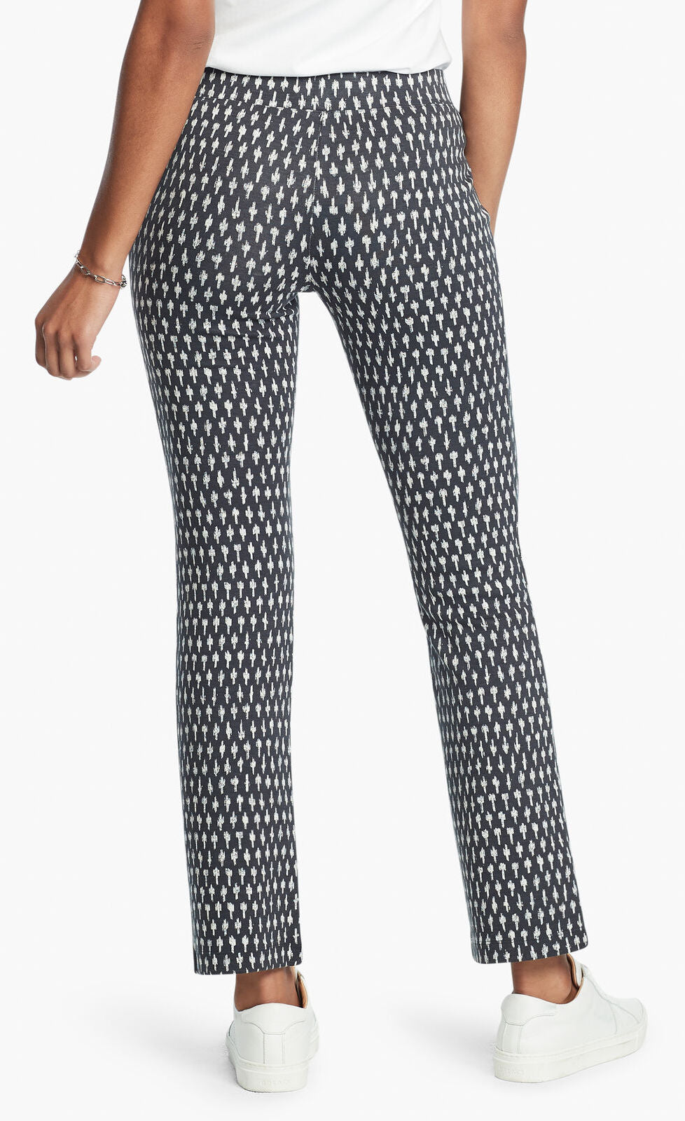 Back, bottom half view of a woman wearing the Nic + Zoe Ponte Ikat Pant. These pants are indigo with white speckled print. They have a straight leg and sit above the ankles.