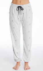 Load image into Gallery viewer, Front bottom half view of a woman wearing the PJ Salvage Lily Rose Banded Pant. The banded pant is a heathered light grey with tiny french bulldog faces printed on it in black and a black tie waistband
