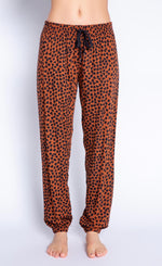 Load image into Gallery viewer, Front view of the bottom half of a woman wearing the PJ Salvage Wild Love Banded Pant. This banded pant is mocha/brown colored with a black heart shaped animal print. It has a black tie waistband.
