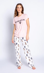 Front full body view of a woman wearing a pink tee from PJ salvage that says My Dog Gets Me. On the bottom the woman is wearing a PJ Salvage Love & Dogs pajama pant with a mix of hipster dogs printed on it.