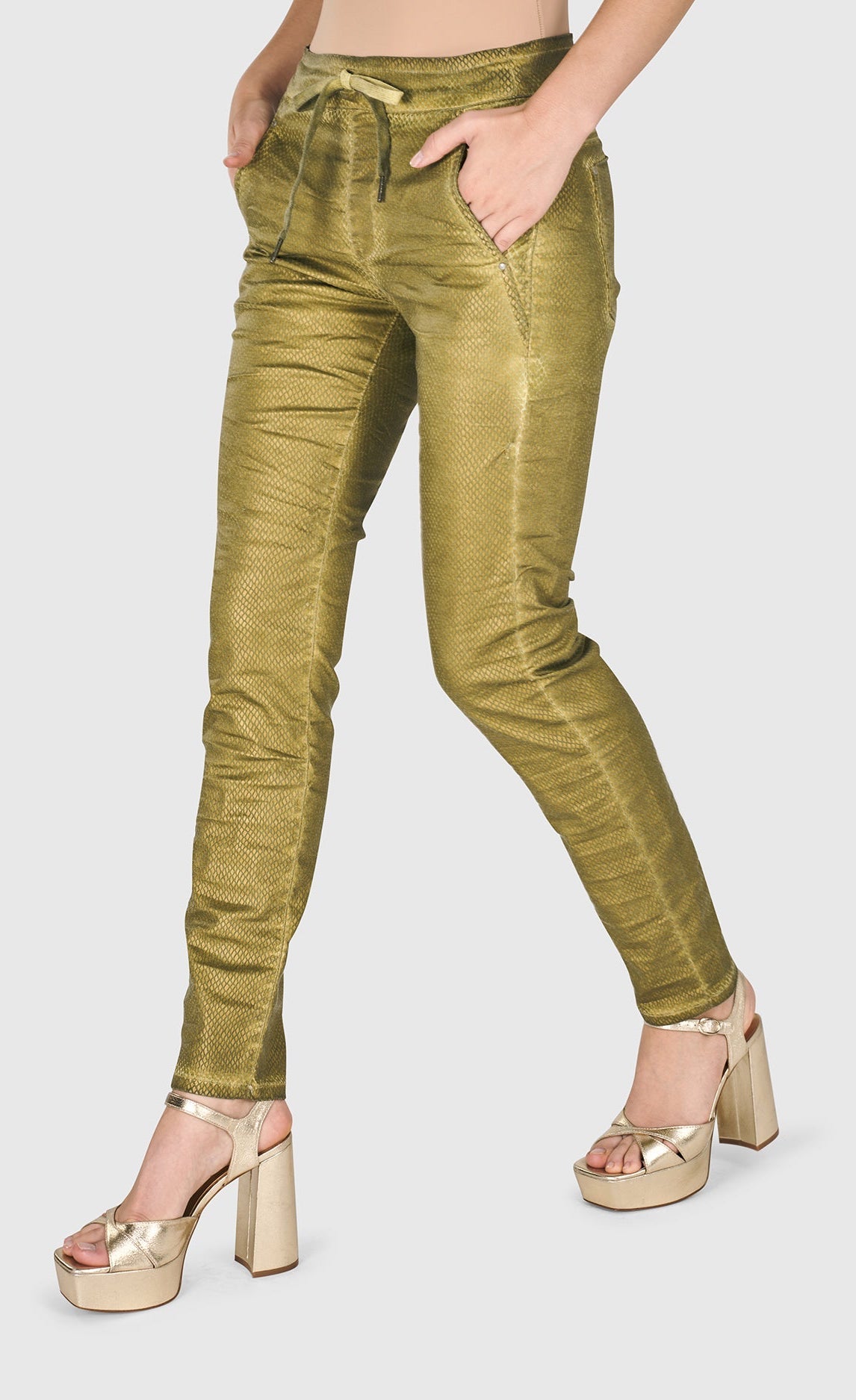 Alembika left sided bottom half view of a woman wearing the alembika iconic stretch jeans in green snake.