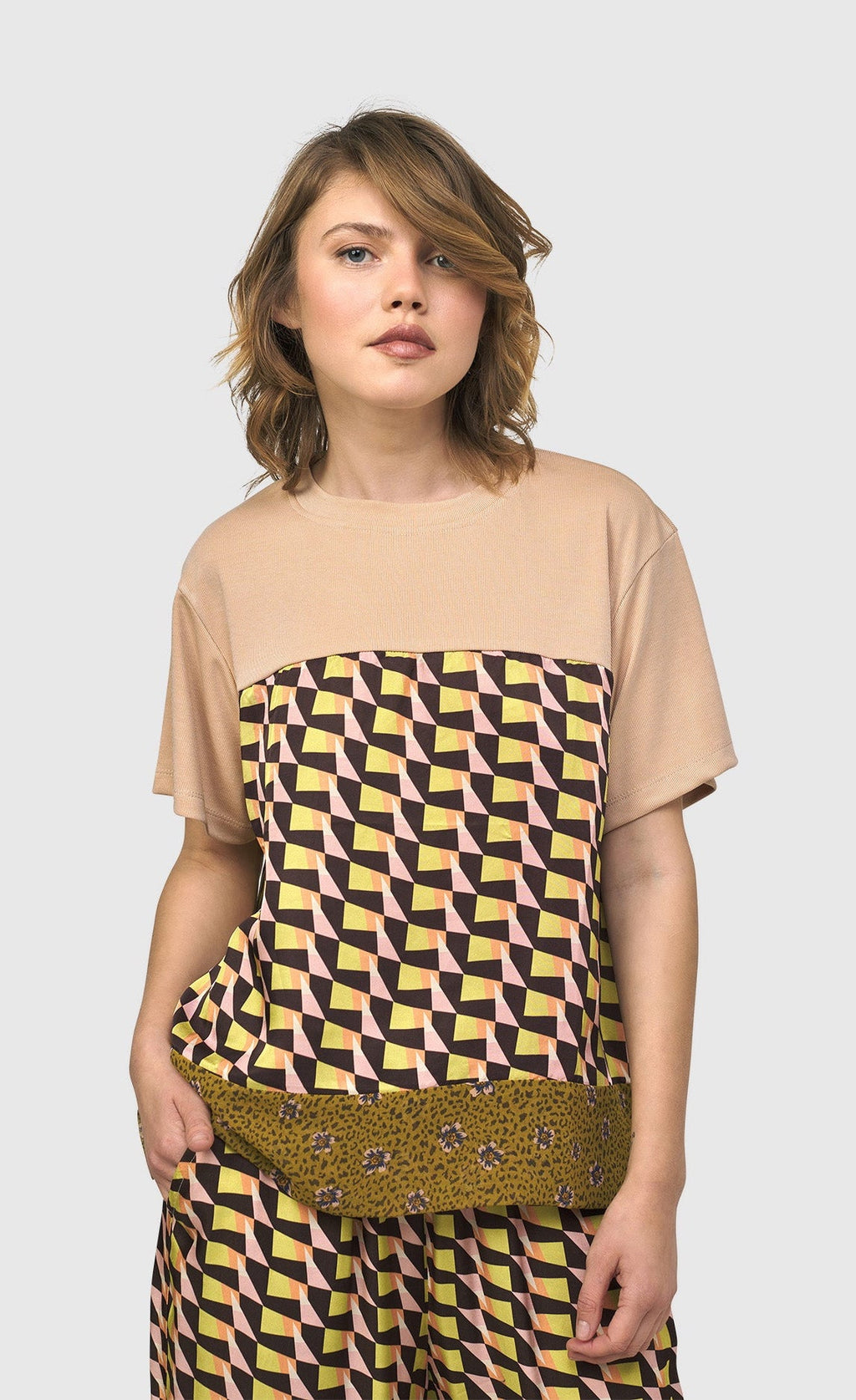 Front top half view of a woman wearing the alembika mix escher boxy tee