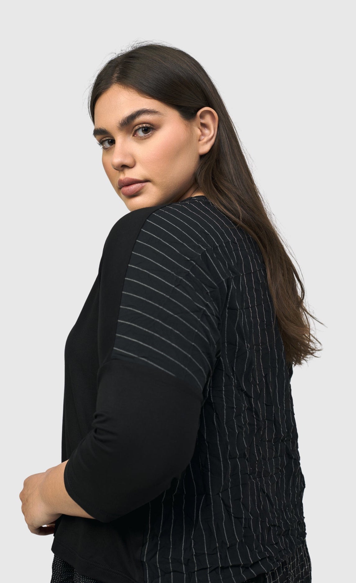 Left side top half view of a woman wearing the alembika striped andromeda cropped cardigan