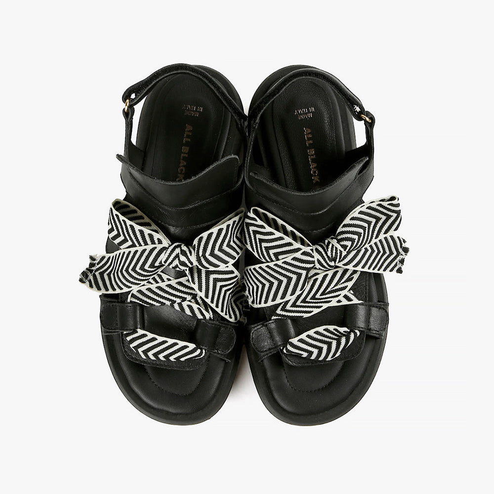 Birdseye view of a pair of the all black footwear bowlace sandal