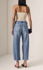 Load image into Gallery viewer, Woman wearing a strapless beige top and light blue jeans from behind on a plain background
