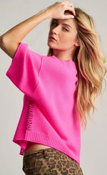 Load image into Gallery viewer, A woman wearing a bright hot pink knit sweater with a side lace-up detail, paired with leopard print pants, against a light gray studio background.
