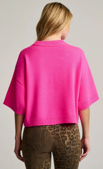 Load image into Gallery viewer, A woman viewed from the back wearing a bright pink cropped knit sweater with wide short sleeves and leopard-print pants against a light gray studio background.
