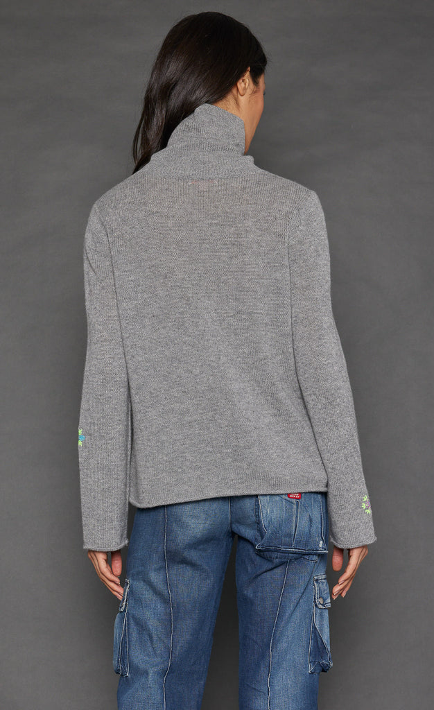 Back top half view of a woman wearing the lisa todd lucky charm sweater in heather grey.