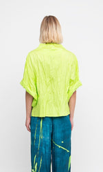 Load image into Gallery viewer, Back top half view of a woman wearing the ozai n ku lime crinkle funnel shirt.
