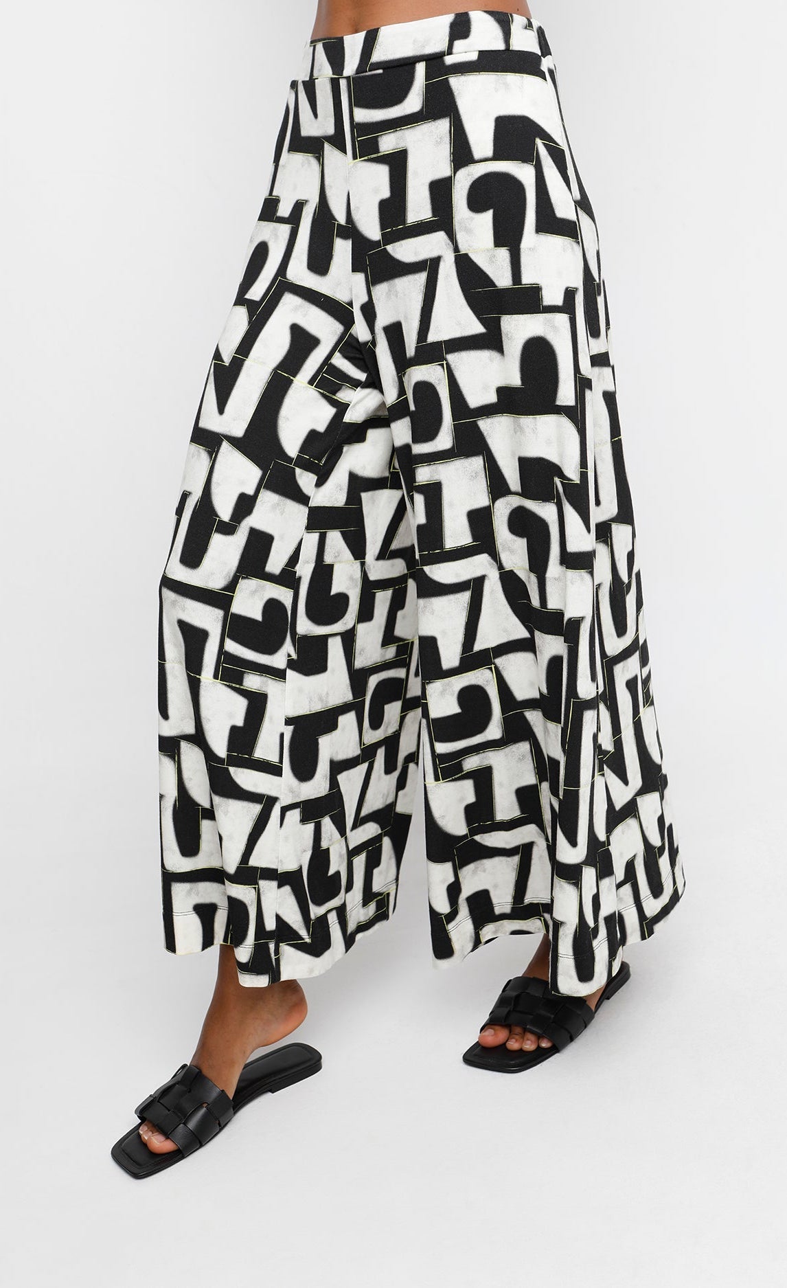 Front bottom half view of a woman wearing the ozai n ku puzzle letterpress palazzo pants