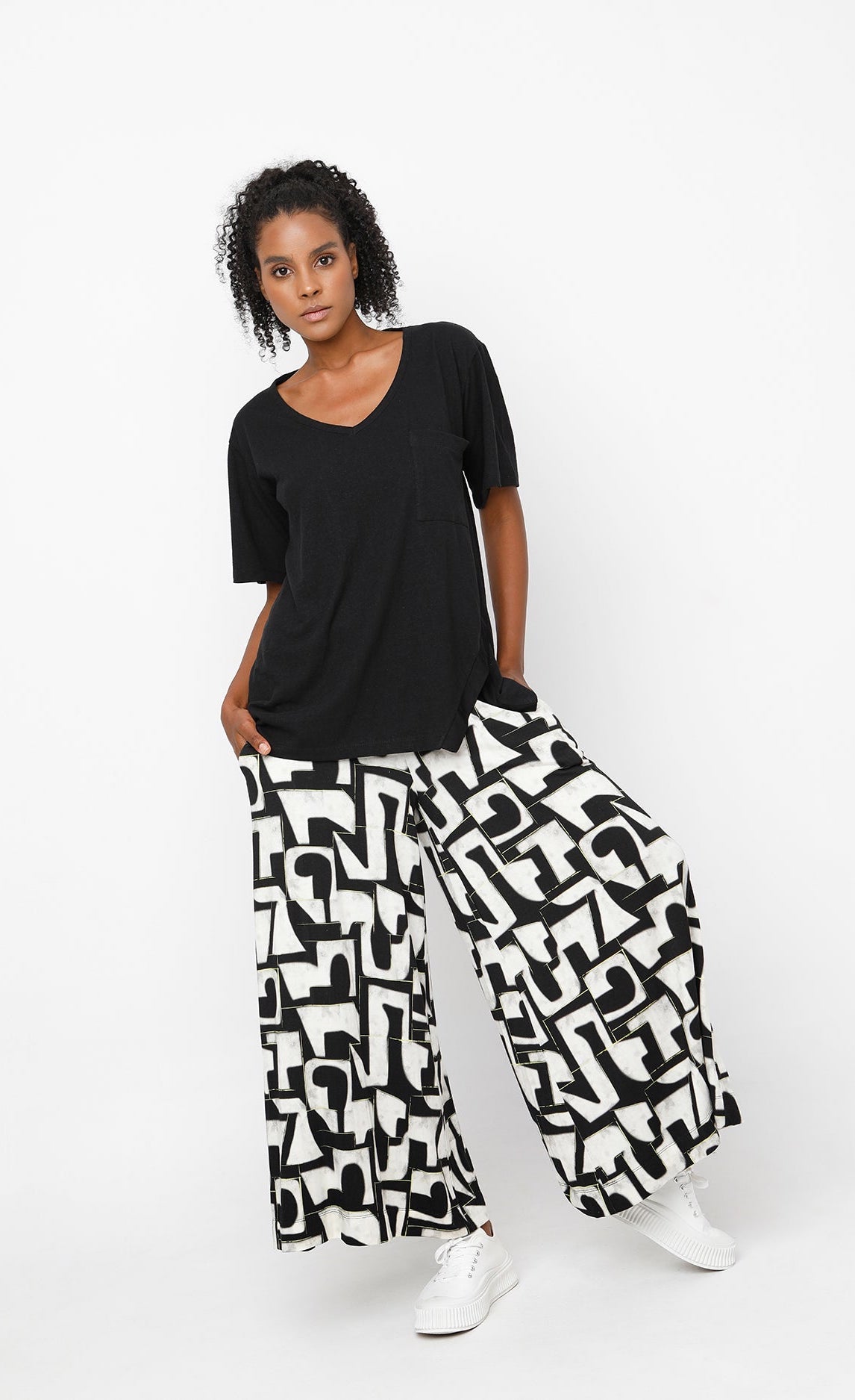 Front full body view of a woman wearing the ozai n ku puzzle letterpress palazzo pants