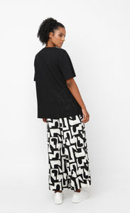 back full body view of a woman wearing the ozai n ku puzzle letterpress palazzo pants