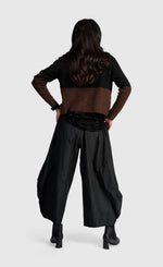 Load image into Gallery viewer, A model shown from the back wearing a color-blocked knit top with black and brown panels, wide-leg black pants, and black ankle boots, set against a plain light gray studio background.
