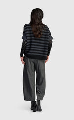Load image into Gallery viewer, A model shown from the back wearing a black and gray striped knit top with textured sleeves, wide-leg charcoal gray trousers, and black ankle boots, set against a plain light gray background.
