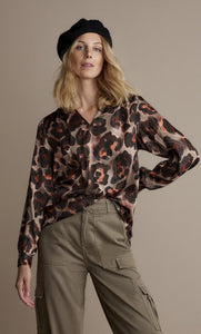 Front top half view of a woman wearing the v-neck animal print top.