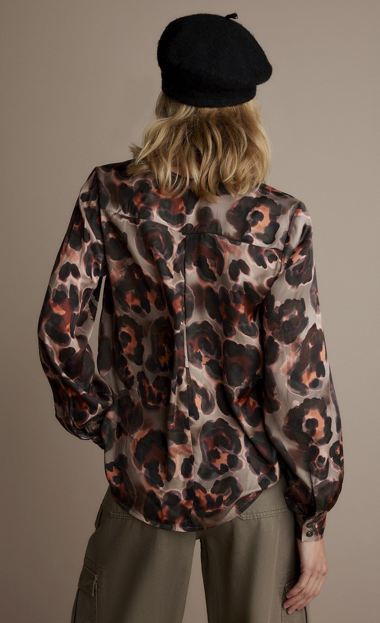 Back top half view of a woman wearing the v-neck animal print top.