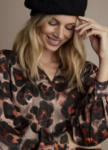 Front close up view of a woman wearing the v-neck animal print top.