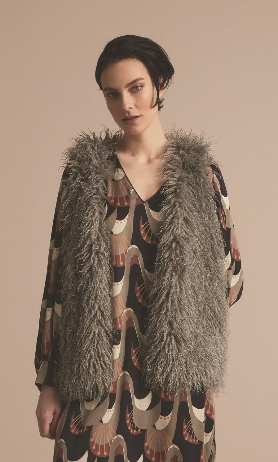 Front top half view of a woman wearing the summum faux fur gilet in clay.