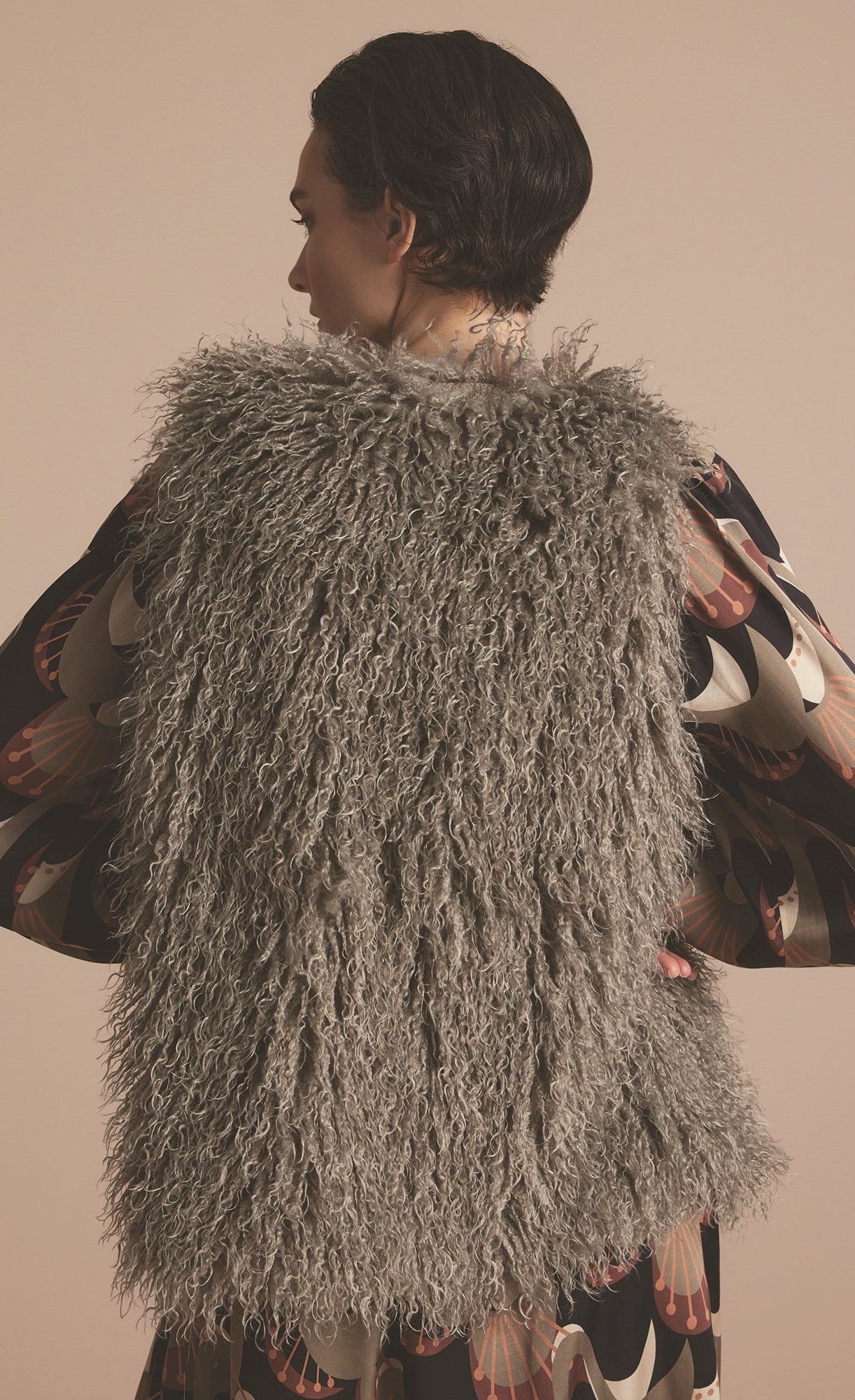Back top half view of a woman wearing the summum faux fur gilet in clay.