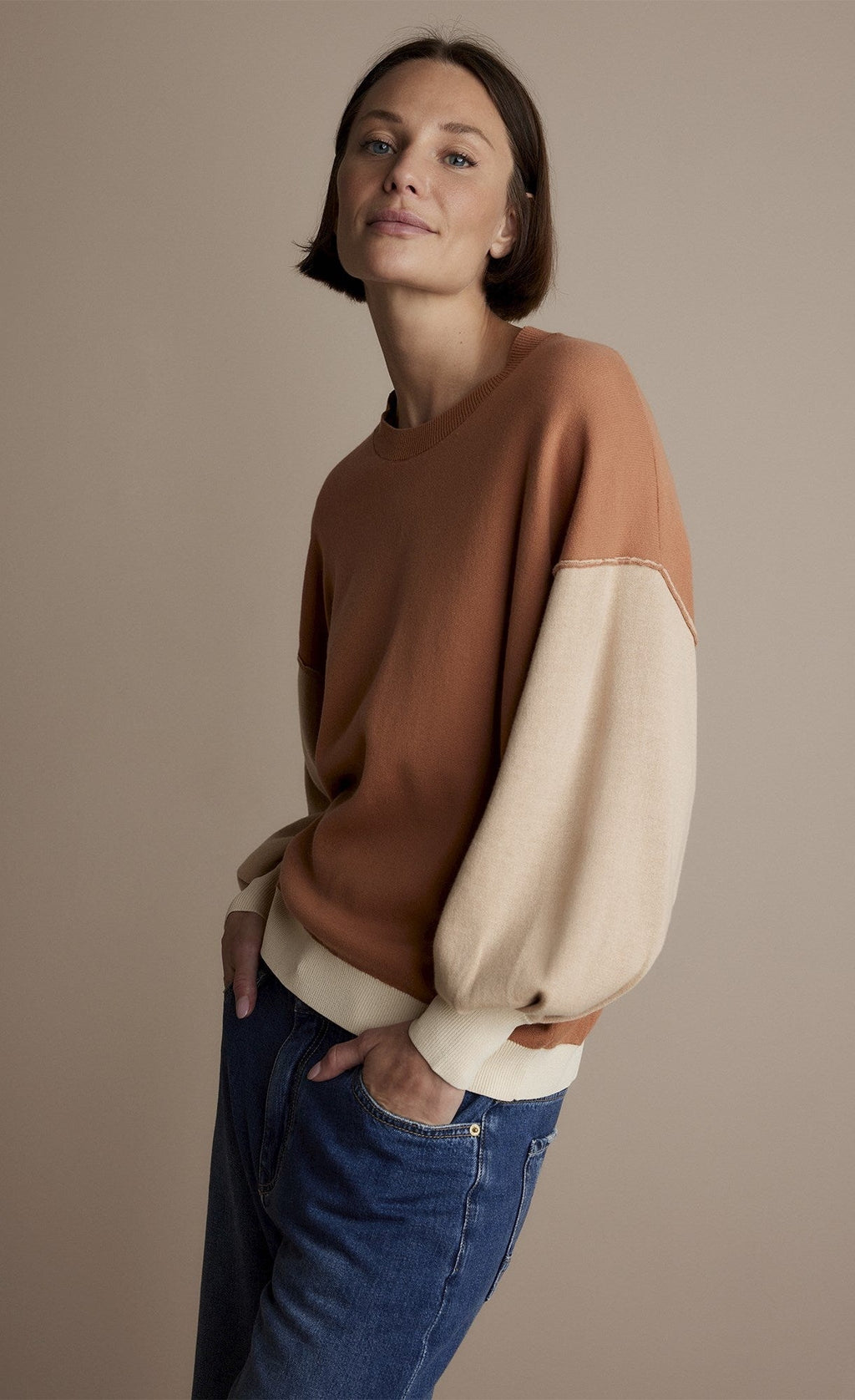 Front top half view of a woman wearing the summum double bed jumper with puff sleeves.