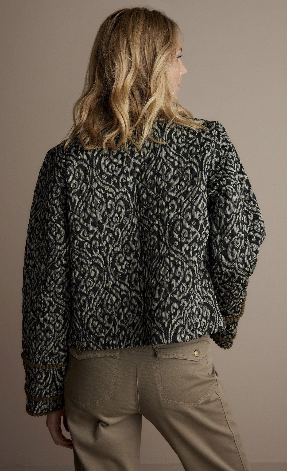 Back top half view of a woman wearing the summum lightly quilted jacket.