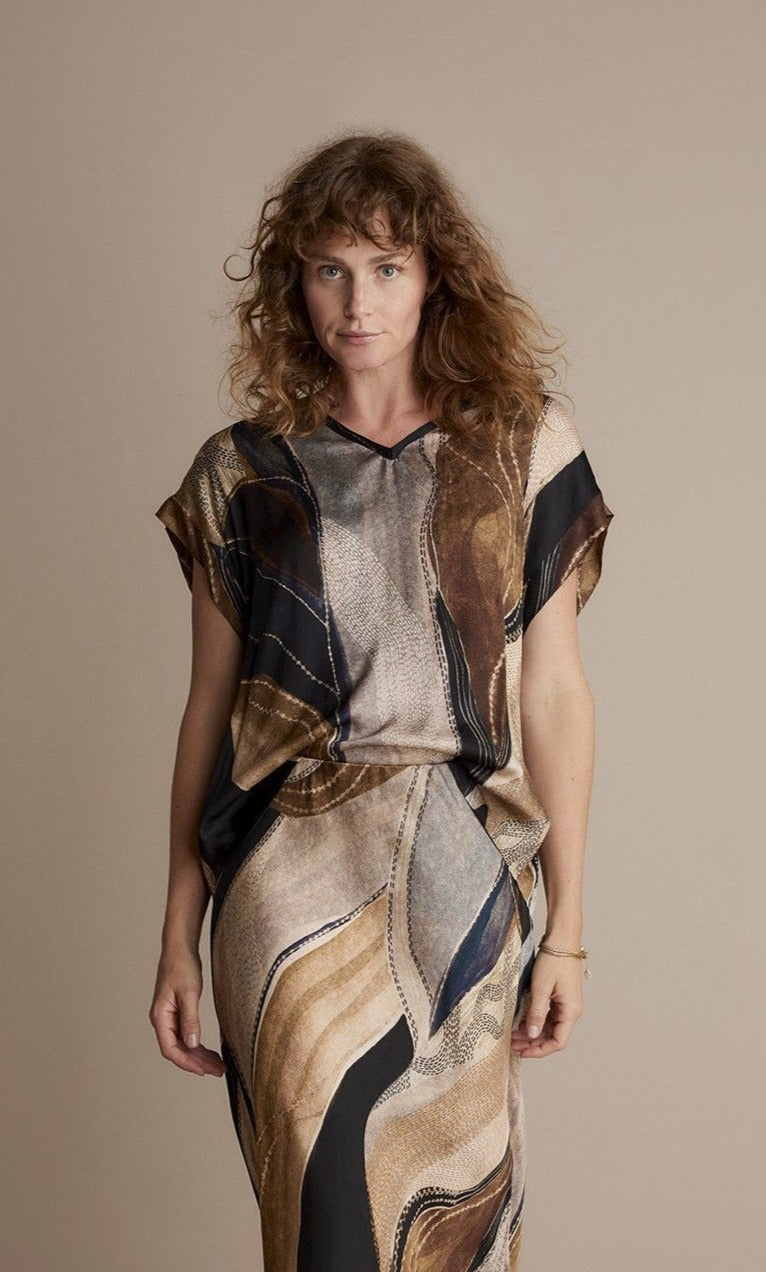 Front top half view of a woman wearing the summum flowy lines sleeveless organic print top
