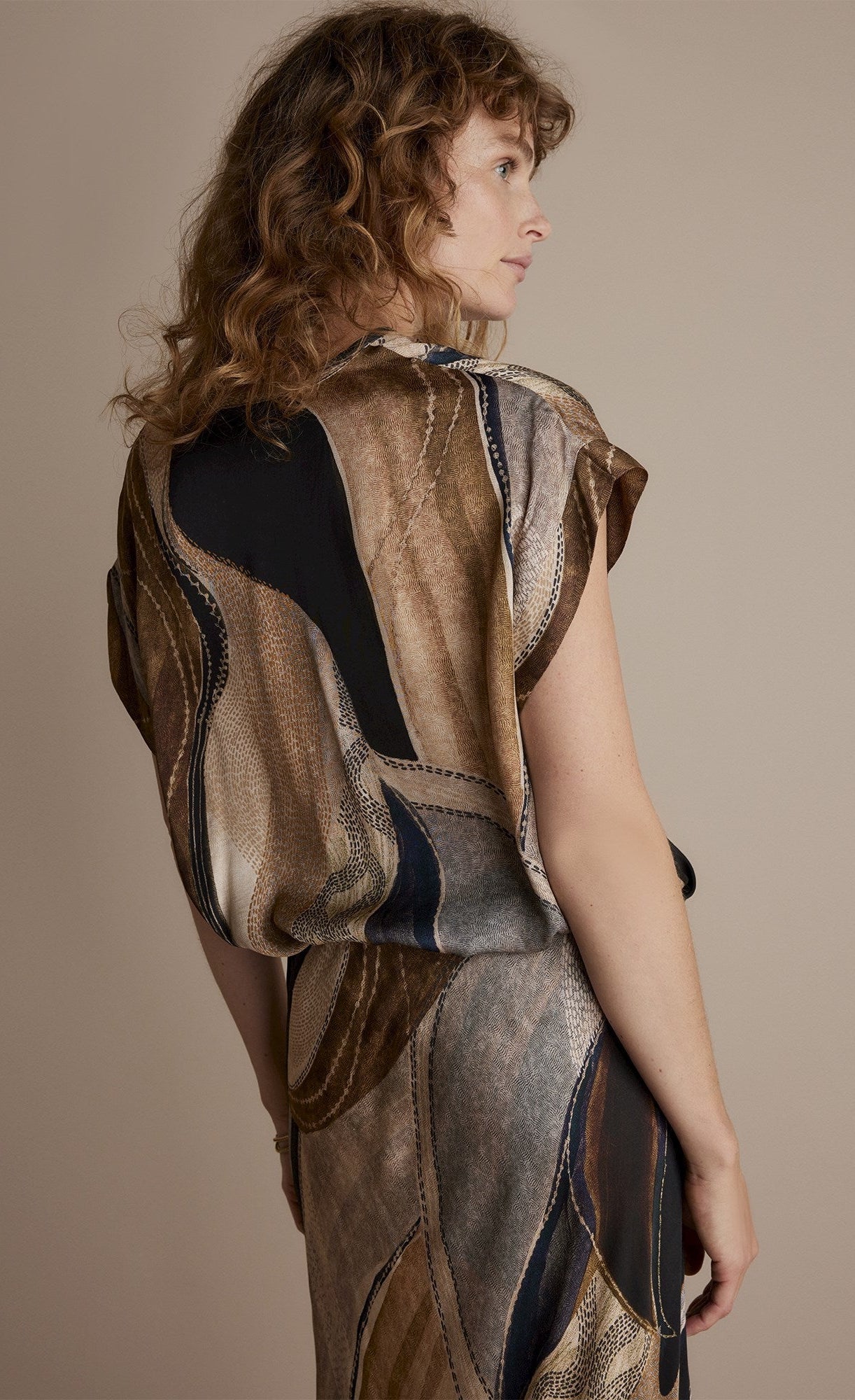 Back top half view of a woman wearing the summum flowy lines sleeveless organic print top
