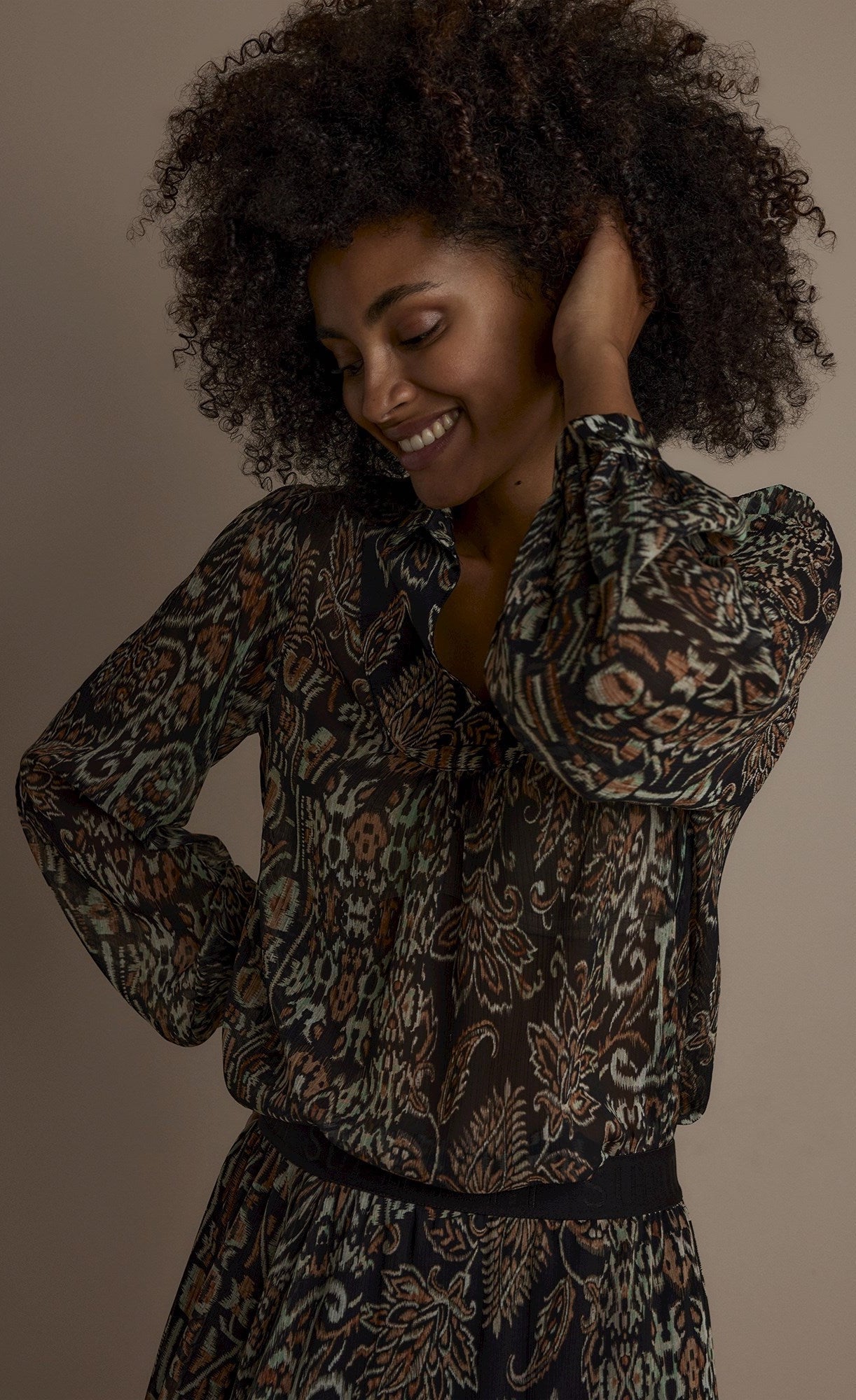 Front top half view of a woman wearing the summum brown print top