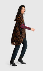 Load image into Gallery viewer, A woman modeling a long-sleeve tunic top with a mixed animal print pattern, featuring a brown and black tiger-stripe design on the body and sleeves, and a red and green paisley pattern on the opposite sleeve, paired with dark jeans and black ankle boots against a light gray background.
