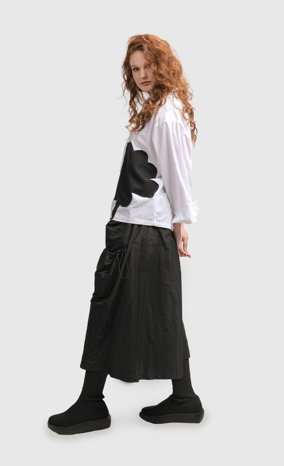 Left side full body view of a woman wearing the Alembika Urban Modern Flower Top
