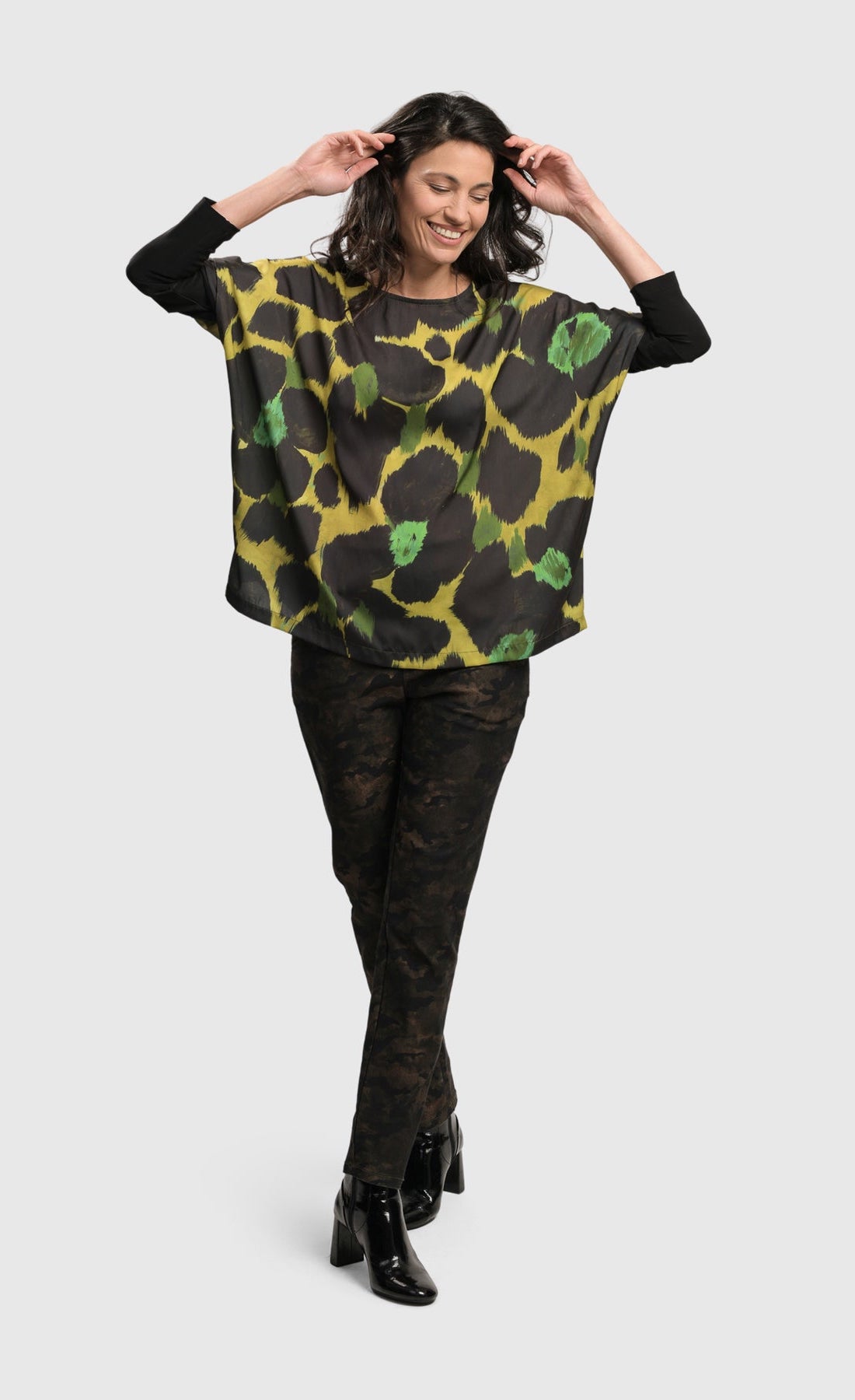 Front full body view of a woman wearing the Alembika Olive Martini Emerald Boxy Tee