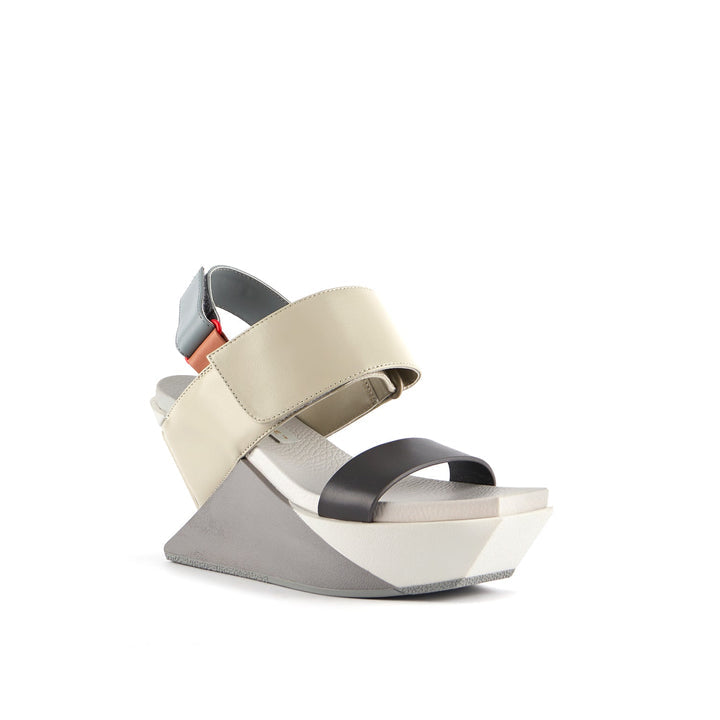 front outer side view of the united nude delta wedge sandals in neutral.