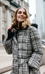 Load image into Gallery viewer, Front close up view of a model walking around town wearing black pants and the nikki jones plaid jeannie coat. This coat is white with black and beige/grey plaid print.
