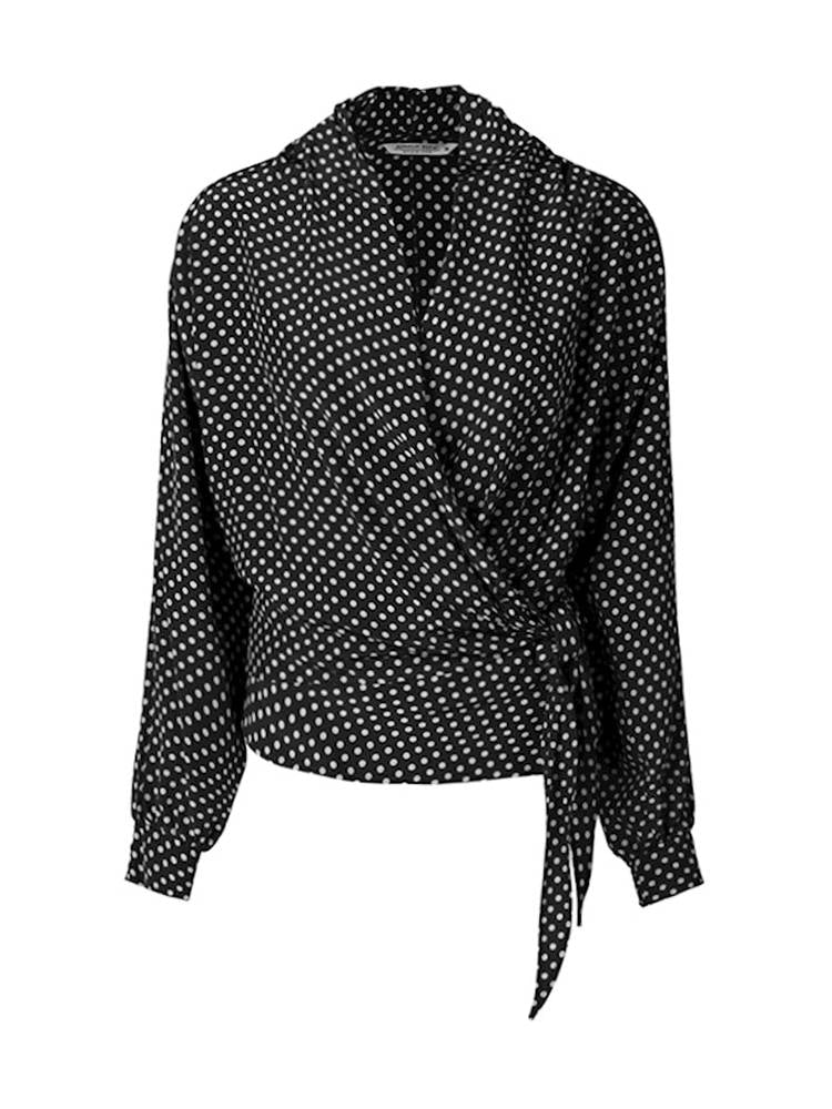 Front view of the summum 2-piece wrap blouse. This blouse has long puffy sleeves with cuffs and a wrap front with a tie closure. The wrap in this image is black with white polka dots.