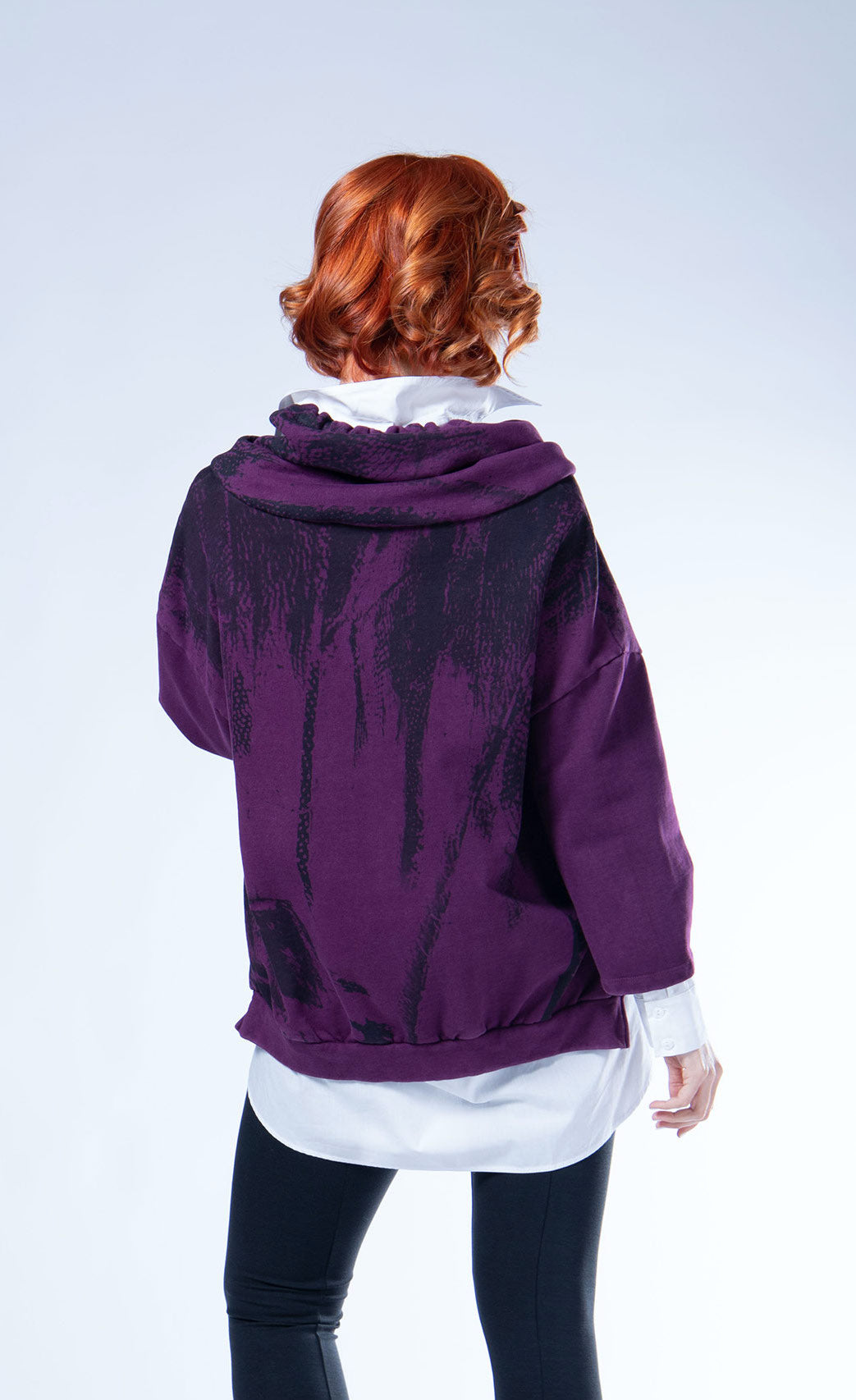 Back top half view of a woman wearing the luukaa aubergine sweatshirt with a faded black print. This sweatshirt has an oversized fit, drop shoulders, and 3/4 length sleeves. The sweatshirt also has a hood and a ribbed hem.