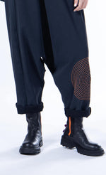 Load image into Gallery viewer, front bottom half view of a woman wearing the luukaa sleeveless circles jumper. This jumper is black with orange stitched circles all over it. The jumper has long pants with a crop crotch.
