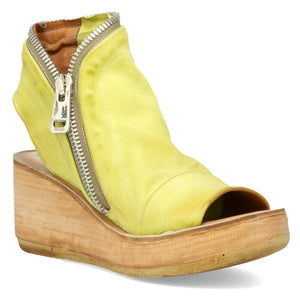 outer front side view of the AS98 naylor wedge sandal in the color zen/yellow. this sandal has a wood-like wedge and leather overing the foot and ankle. The sandal has an open toe and heel and the outer side of the sandal has a zipper. 