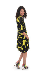 Load image into Gallery viewer, Right side, full body view of a woman wearing the alembika art print wonderful collar dress. This dress is lime with a black swirl print. The model has her hand in the front right pocket..

