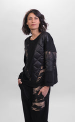 Load image into Gallery viewer, Front top half view of a woman wearing the Alembika Bronze Top. This boxy top has 3/4 sleeves, a crew neck, and a mix of solid, printed, and quilted fabric. The top is black with bronze print.
