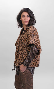 Left side top half view of a woman wearing the Alembika kenya kimono in a brown cheetah print. This kimono has a single front button, short sleeves, and a fuzzy appearance.