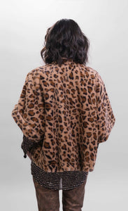 Back top half view of a woman wearing the Alembika kenya kimono in a brown cheetah print. This kimono has a single front button, short sleeves, and a fuzzy appearance.