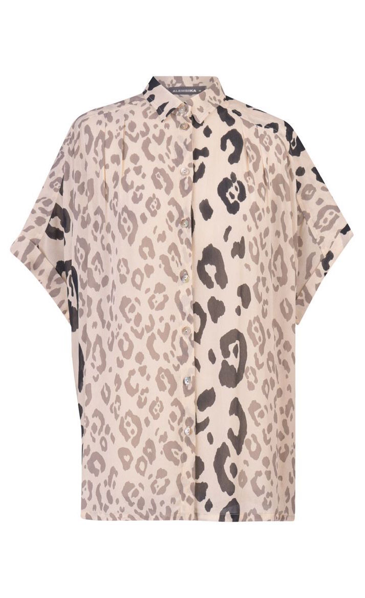 Front view of the alembika Cheetah Print Button Down Top. This top has different panels of black and taupe cheetah print on a creme background. The top has a button down front and short dolman sleeves.